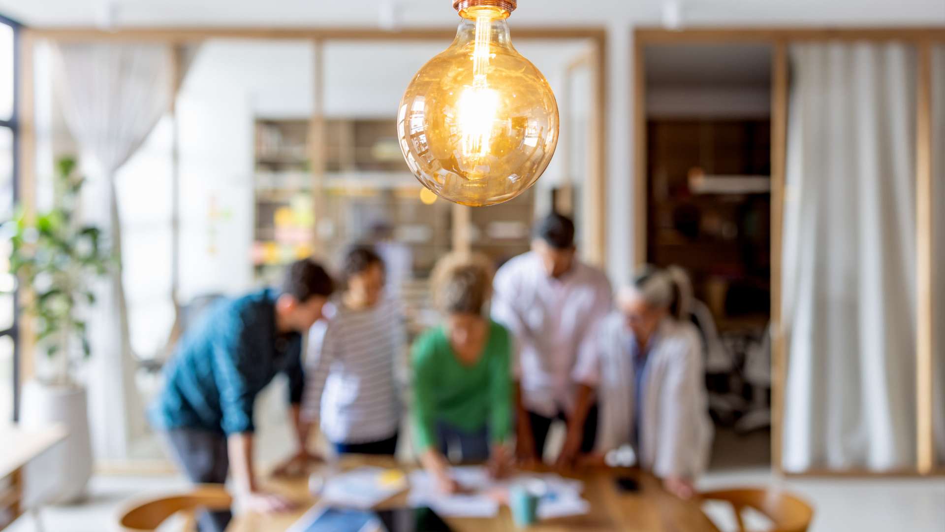 A group gathered around a table looking at papers with a lighbulb in the foreground