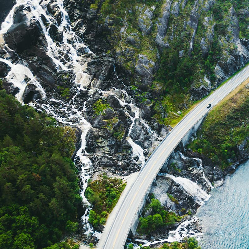 Car driving down a road next to the ocean